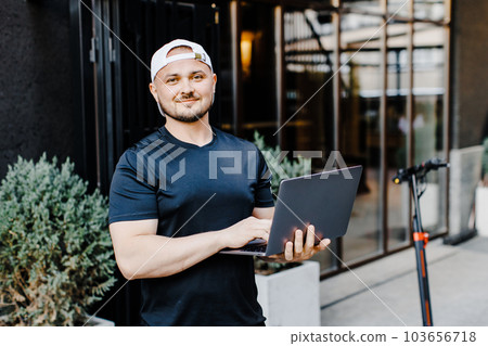 Handsome man works online freelancer or businessman holding laptop and standing near electric scooter. Ecology and clean ecological mode of transport 103656718