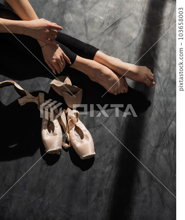 Faceless ballerina sits on the floor and puts on pointe shoes. Faceless ballerina sits on the floor and puts on pointe shoes. 103658003