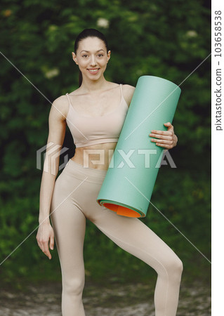 Pretty lady training in a summer park. Brunette doing yoga. Gitl in a sportsuit. 103658538