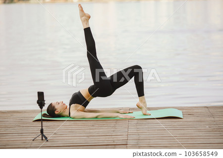 Pretty lady training in a summer park. Brunette doing yoga. Girl shoots a blog. 103658549