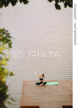 Pretty lady training in a summer park. Brunette doing yoga. Girl in a sportsuit. 103658552