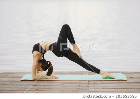 Pretty lady training in a summer park. Brunette doing yoga. Girl in a sportsuit. 103658556