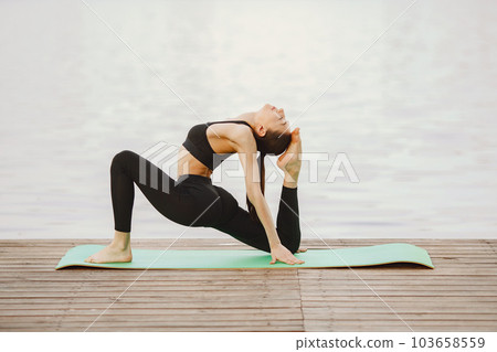 Pretty lady training in a summer park. Brunette doing yoga. Girl in a sportsuit. 103658559