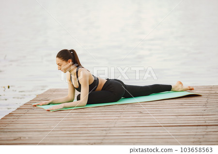 Pretty lady training in a summer park. Brunette doing yoga. Girl in a sportsuit. 103658563