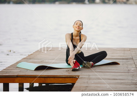 Pretty lady training in a summer park. Brunette doing yoga. Girl in a sportsuit. 103658574