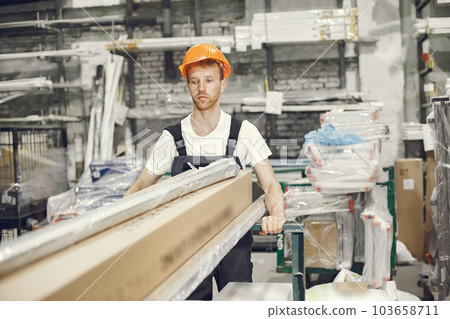 Industrial worker indoors in factory. Young technician with orange hard hat. 103658711