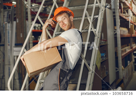 Industrial worker indoors in factory. Young technician with orange hard hat. 103658716
