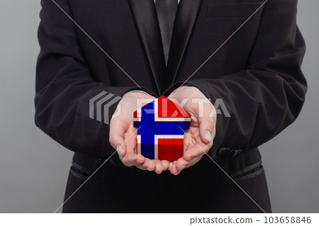 Norwegian person holding wooden house with flag of Norway Finance, investment, mortgage 103658846