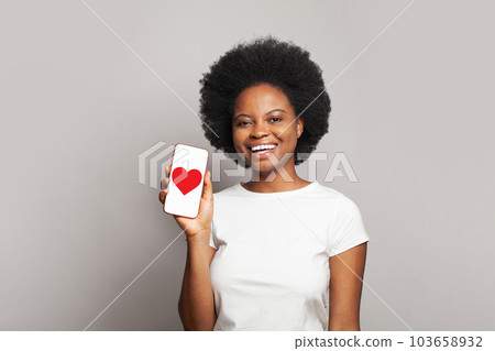 Happy woman showing modern smartphone with red heart on display 103658932