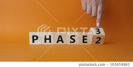 From Phase 2 to 3 symbol. Businessman Hand points at wooden cubes with words Phase 2 and Phase 3. Beautiful orange background. Business and Phase concept. Copy space 103659965