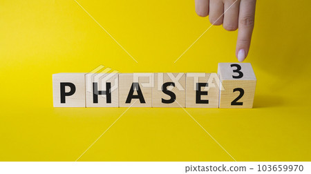 From Phase 2 to 3 symbol. Businessman Hand points at wooden cubes with words Phase 2 and Phase 3. Beautiful yellow background. Business and Phase concept. Copy space 103659970