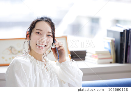 一個女人坐在沙發上使用智能手機 103660118