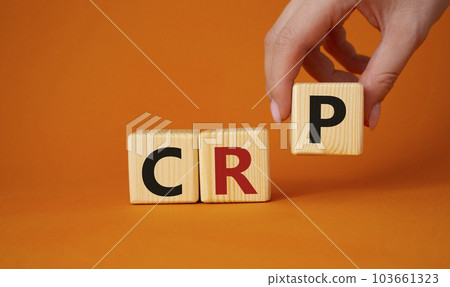 CRP - C-Reactive Protein Test symbol. Wooden cubes with word CRP. Doctor hand. Beautiful orange background. Medical and C-Reactive Protein Test concept. Copy space. 103661323