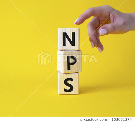 NPS - Net Promoter Score symbol. Wooden cubes with words NPS. Businessman hand. Beautiful yellow background. Business and NPS concept. Copy space. 103661374