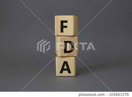 FDA - Food Drug Administration symbol. Wooden cubes with word FDA. Beautiful grey background. Medical and Food Drug Administration concept. Copy space. FDA - Food Drug Administration symbol. Wooden cubes with word FDA. Beautiful grey background. Medical and Food Drug Administration concept. Copy space. 103661376