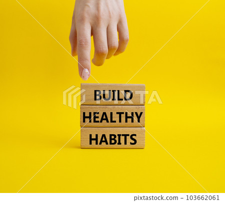 Healthy habits symbol. Concept word Build Healthy habits on wooden blocks. Doctor hand. Beautiful yellow background. Healthy lifestyle and Healthy habits concept. Copy space 103662061