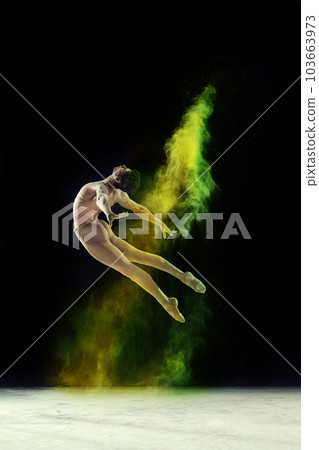 Muscular young man, professional ballet dancer in motion, dancing with colorful powder explosion against black studio background 103663973