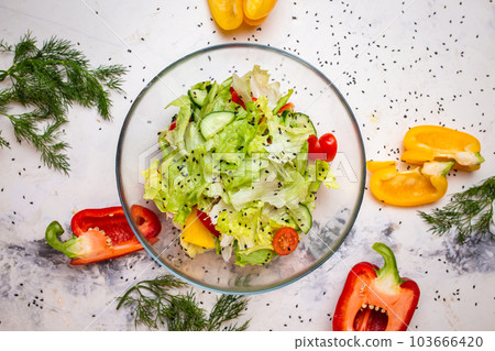 Vegetarian salad with fresh vegetables, lettuce and sesame with tomatoes. Salad in a glass cup top view. 103666420