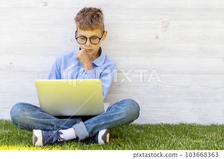 A boy using a laptop outdoors A boy using a laptop outdoors 103668363
