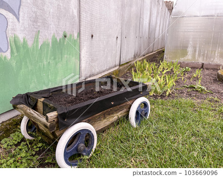 a small decorative cart in the garden in early spring 103669096