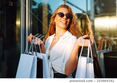 Fashion woman with shopping bags walking around city after shopping. Sale, lifestyle concept. 103669162