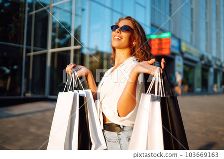 Fashion woman with shopping bags walking around city after shopping. Sale, lifestyle concept. 103669163