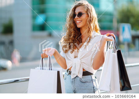 Fashion woman with shopping bags walking around city after shopping. Sale, lifestyle concept. 103669164