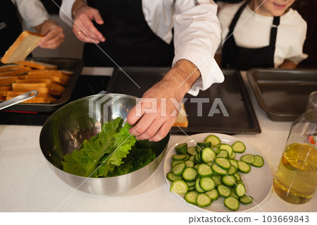 close-up shot. hands holding fresh local organic lettuce leaf and cucumber at cooking class close-up shot. hands holding fresh local organic lettuce leaf and cucumber at cooking class 103669843