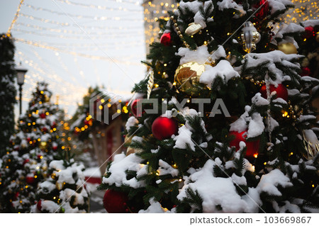 beautiful multi-colored toys on a Christmas tree against the background of lights and snow beautiful multi-colored toys on a Christmas tree against the background of lights and snow 103669867