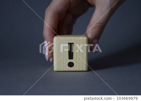 Exclamation mark symbol. Exclamation mark on wooden cubes. Businessman hand. Beautiful grey background. Business and Exclamation mark concept. Copy space. Exclamation mark symbol. Exclamation mark on wooden cubes. Businessman hand. Beautiful grey background. Business and Exclamation mark concept. Copy space. 103669979