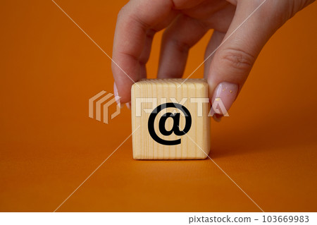 At symbol. At sign on wooden blocks. Businessman hand. Beautiful orange background. Business and at sign concept. Copy space At symbol. At sign on wooden blocks. Businessman hand. Beautiful orange background. Business and at sign concept. Copy space 103669983