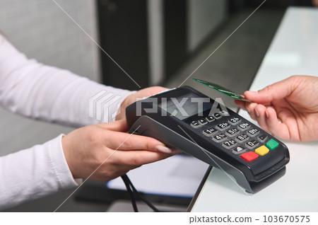 Selective focus on POS terminal, credit card reader in the hands of a manager, saler, retailer holding out for cashless payment view NFC technology. People. Business. Finance. Near field communication Selective focus on POS terminal, credit card reader in the hands of a manager, saler, retailer holding out for cashless payment view NFC technology. People. Business. Finance. Near field communication 103670575