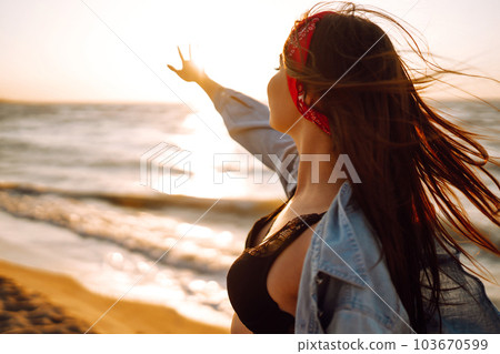 Attractive happy young woman in white t shirt flying hair enjoying her free time at sunset outdoor. Attractive happy young woman in white t shirt flying hair enjoying her free time at sunset outdoor. 103670599