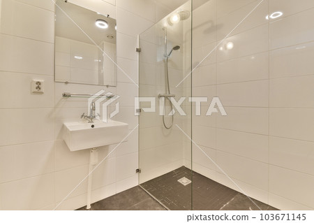 a modern bathroom with white tiles and marble flooring, including a glass shower stall on the right hand side 103671145