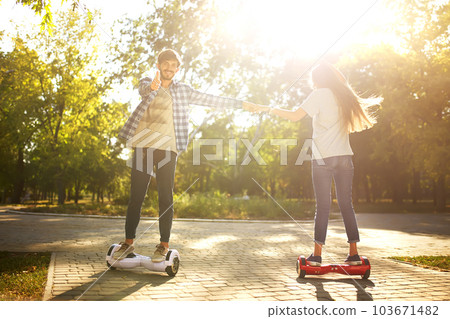 Young man and woman riding on the Hoverboard in the park. content technologies. a new movement. 103671482