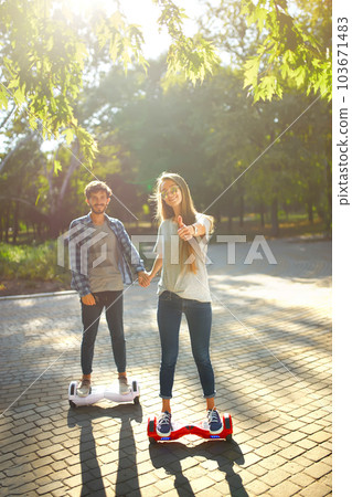 Young man and woman riding on the Hoverboard in the park. content technologies. a new movement. Young man and woman riding on the Hoverboard in the park. content technologies. a new movement. 103671483