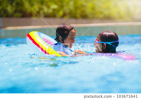 Child in swimming pool on toy ring. Kids swim. 103671641
