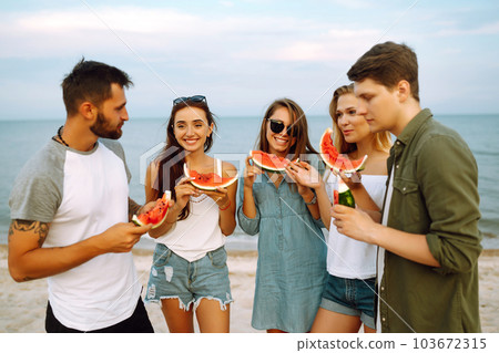 Young friends relaxing on the beach and eating watermelon. People, summer lifestyle 103672315