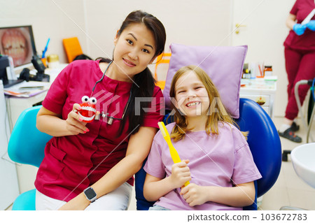 Cheerful pediatric dentist with a patient. training in proper brushing 103672783