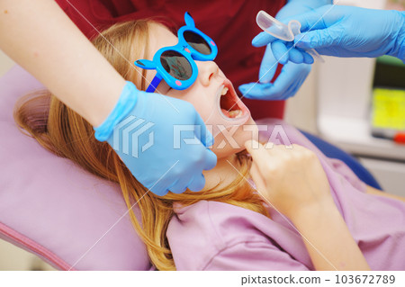 The pediatric dentist installs cheek and lip retractor for takes photos 103672789