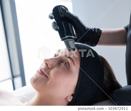 Woman on ultrasonic cleaning procedure. Hardware cosmetology.  103672911