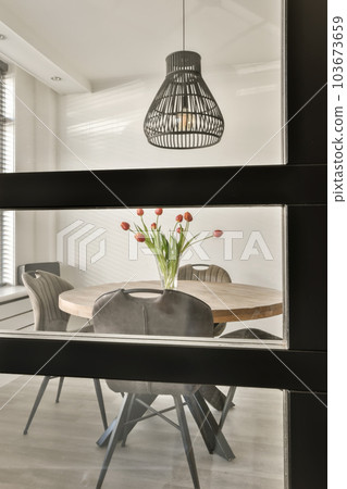 a dining room with chairs and a table in the middle of the room, there is a black pendant light hanging over it 103673659
