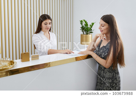 Female receptionist at reception desk with a client in a modern office 103673988