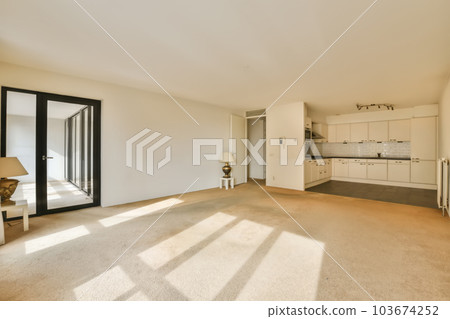 an empty living room with white walls and beige carpet, there is no one person in the room to be seen 103674252