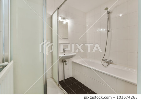 a white bathroom with black tile flooring and wall to wall glass shower stall door in the bathtub is next to the sink a white bathroom with black tile flooring and wall to wall glass shower stall door in the bathtub is next to the sink 103674265