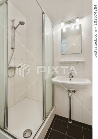 a bathroom with a sink, mirror and shower stall in the corner area on the left side of the room 103674284
