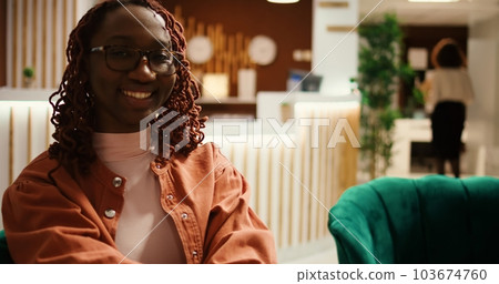 Portrait of happy smiling tourist on vacation sitting in modern welcoming hotel lounge. Relaxed tourist on vacation sitting in cozy lobby, waiting to be given a room, close up Portrait of happy smiling tourist on vacation sitting in modern welcoming hotel lounge. Relaxed tourist on vacation sitting in cozy lobby, waiting to be given a room, close up 103674760
