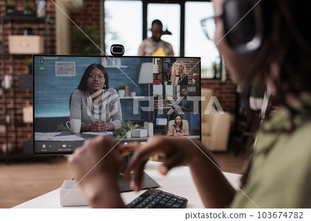 Closeup of african american freelancer with wireless headphones in online interview with startup owner and human resources team. Woman in video call conference working remote from home. 103674782