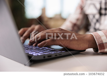 Closeup of male programmer writing code on laptop keyboard while working remote from home living room. Selective focus on african american hands typing and coding software on portable computer. Closeup of male programmer writing code on laptop keyboard while working remote from home living room. Selective focus on african american hands typing and coding software on portable computer. 103674832
