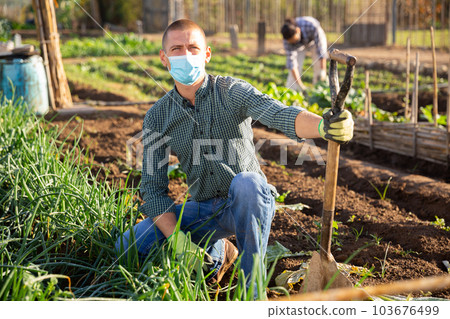 Portrait of male farmer in protective mask with shovel on farm field 103676499